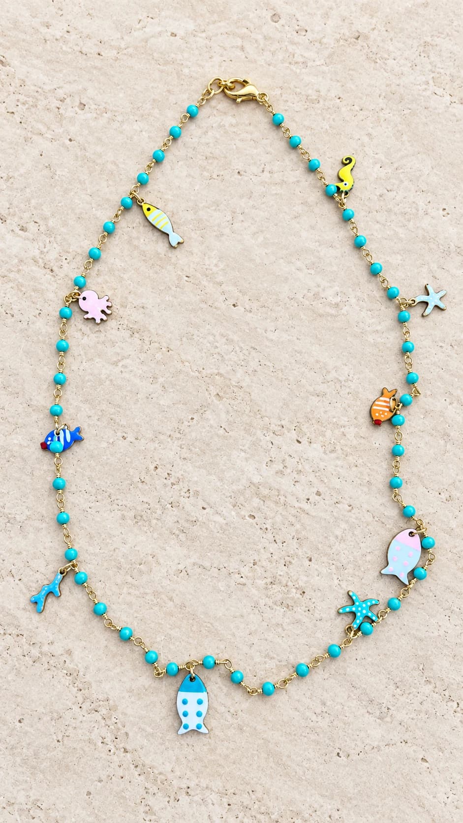 Perline turchesi e trasparenti, pendenti marini colorati e chiusura a moschettone.