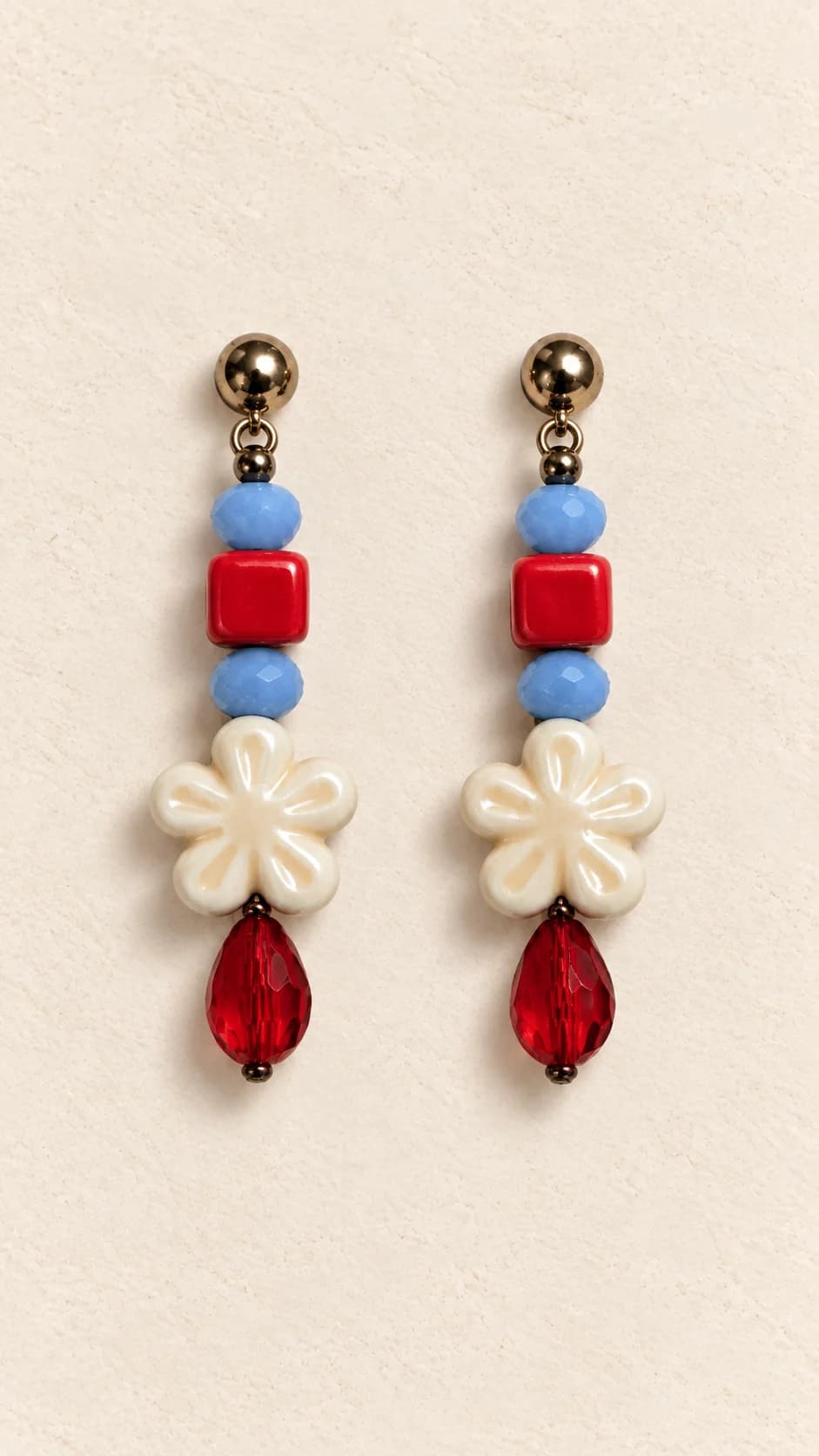 Coppia con elementi rossi e blu, fiori chiari a più petali e gocce rosse allungate.