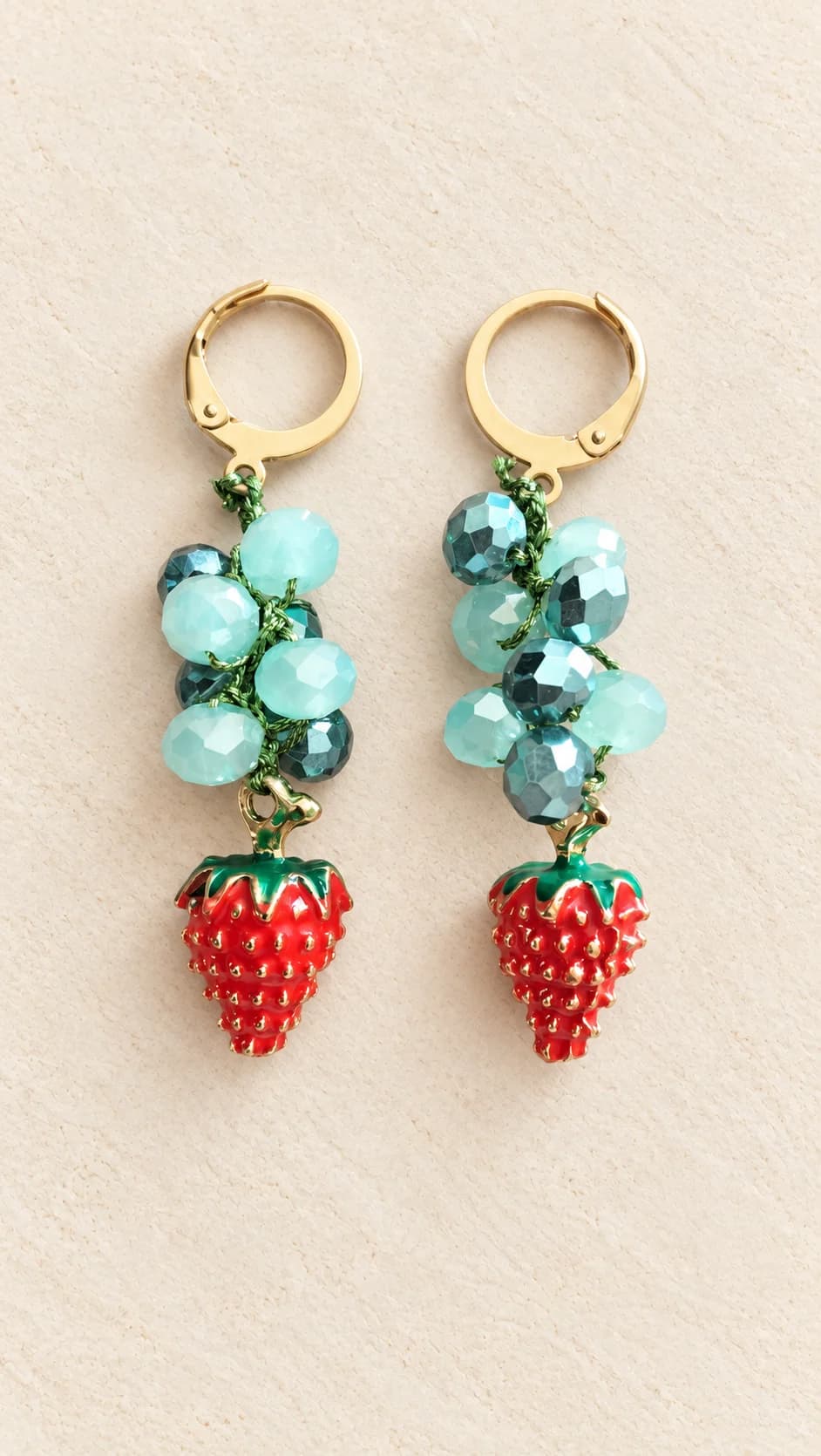 Coppia con attacchi a cerchio dal tono dorato, gruppi di elementi verdi e pendenti rossi a forma di fragola.