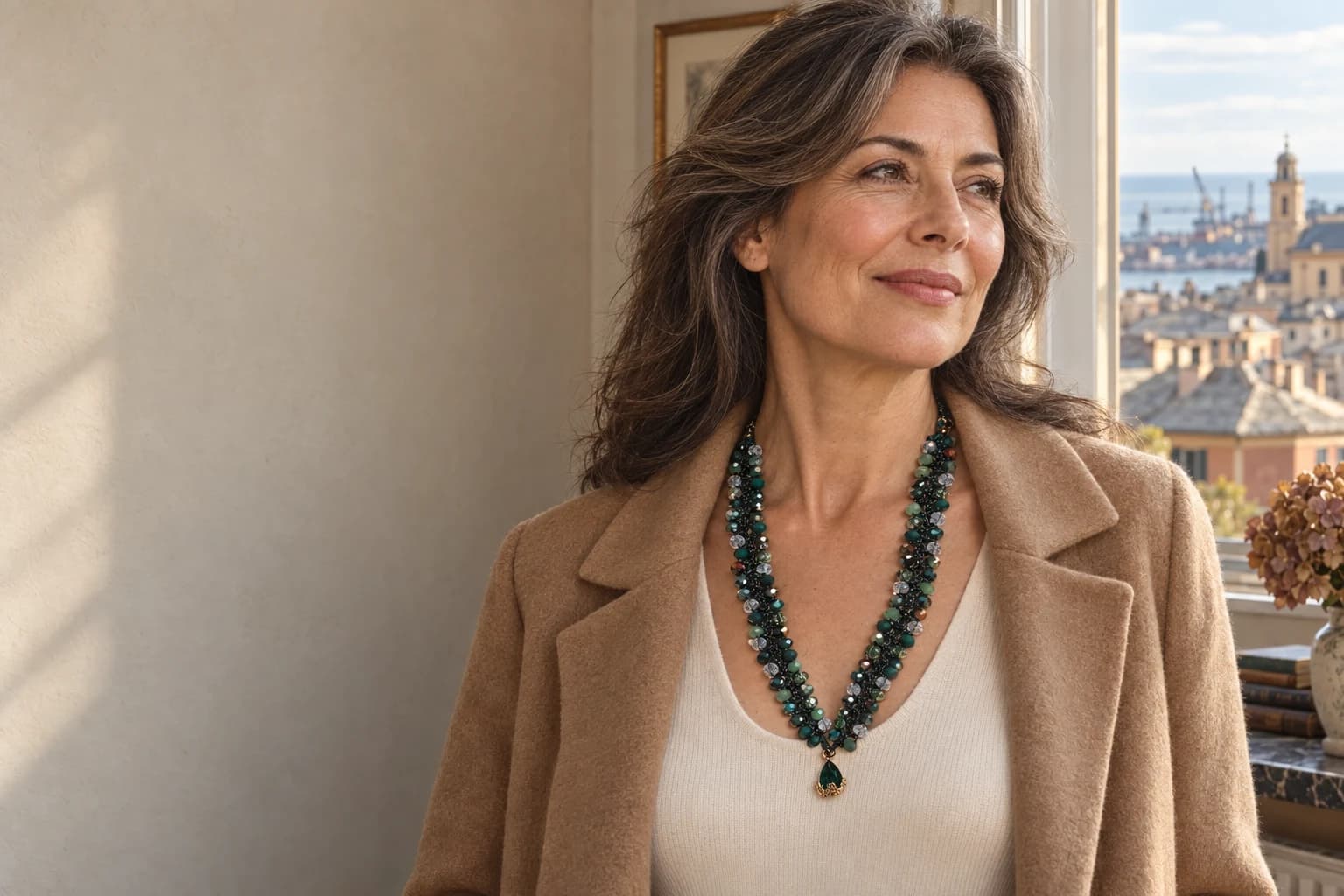 Una donna indossa la collana verde Bosco su una maglia crema, nella luce calda di un interno genovese