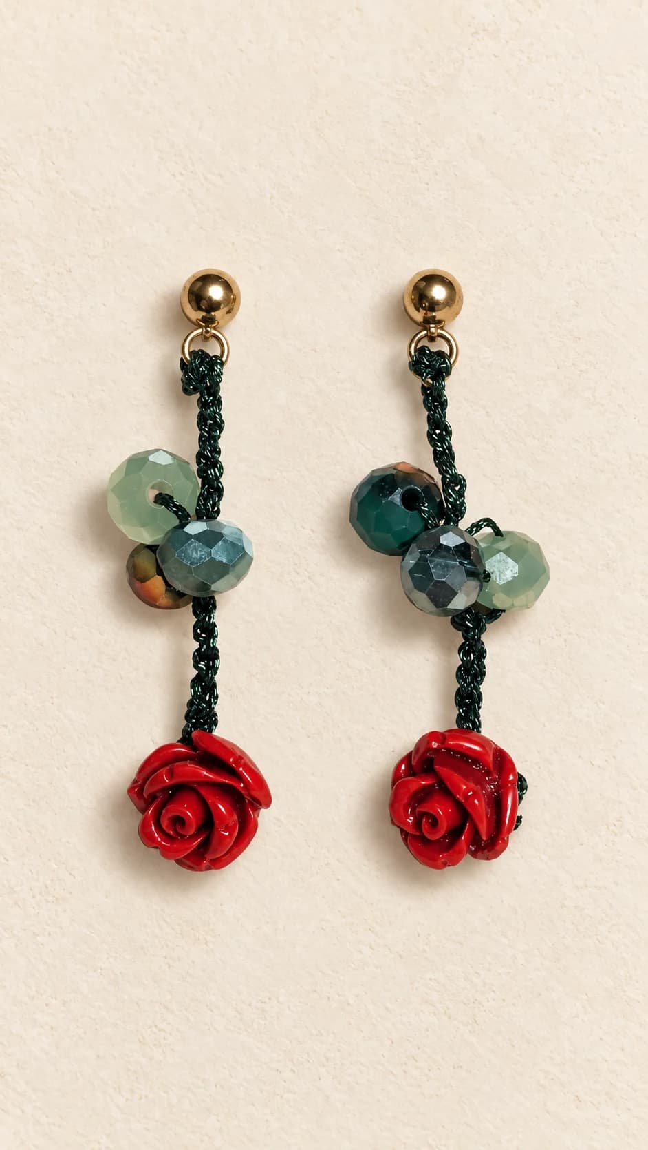 Coppia di orecchini pendenti con elementi verdi sfaccettati, collegamenti scuri e rose rosse in rilievo.