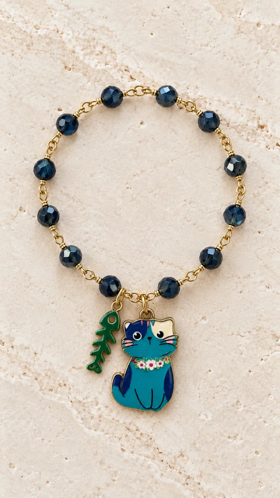 Bracciale con elementi blu scuro sfaccettati, pendente grande a forma di gatto blu e piccolo charm a lisca di pesce.
