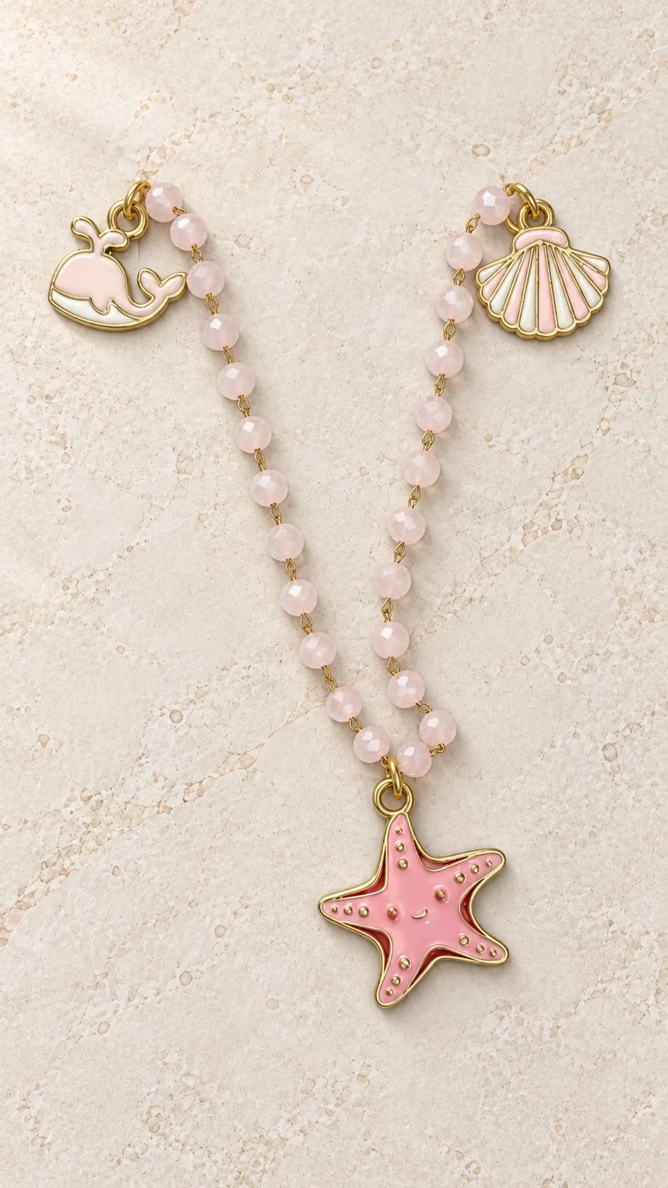Collana con elementi rosa chiaro sfaccettati, pendente centrale a stella marina e dettagli laterali a conchiglia e balena.