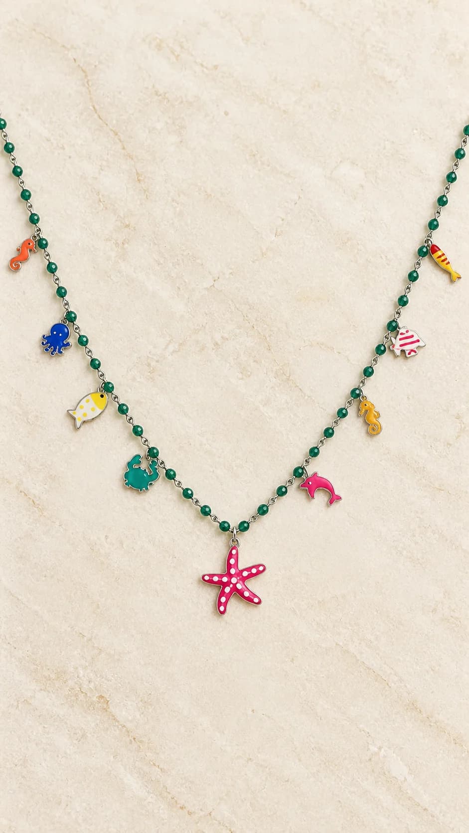 Elementi verdi, pendenti marini e grande stella rosa a pois. La scheda riguarda la sola collana in basso nella foto originale; gli altri gioielli non sono inclusi.