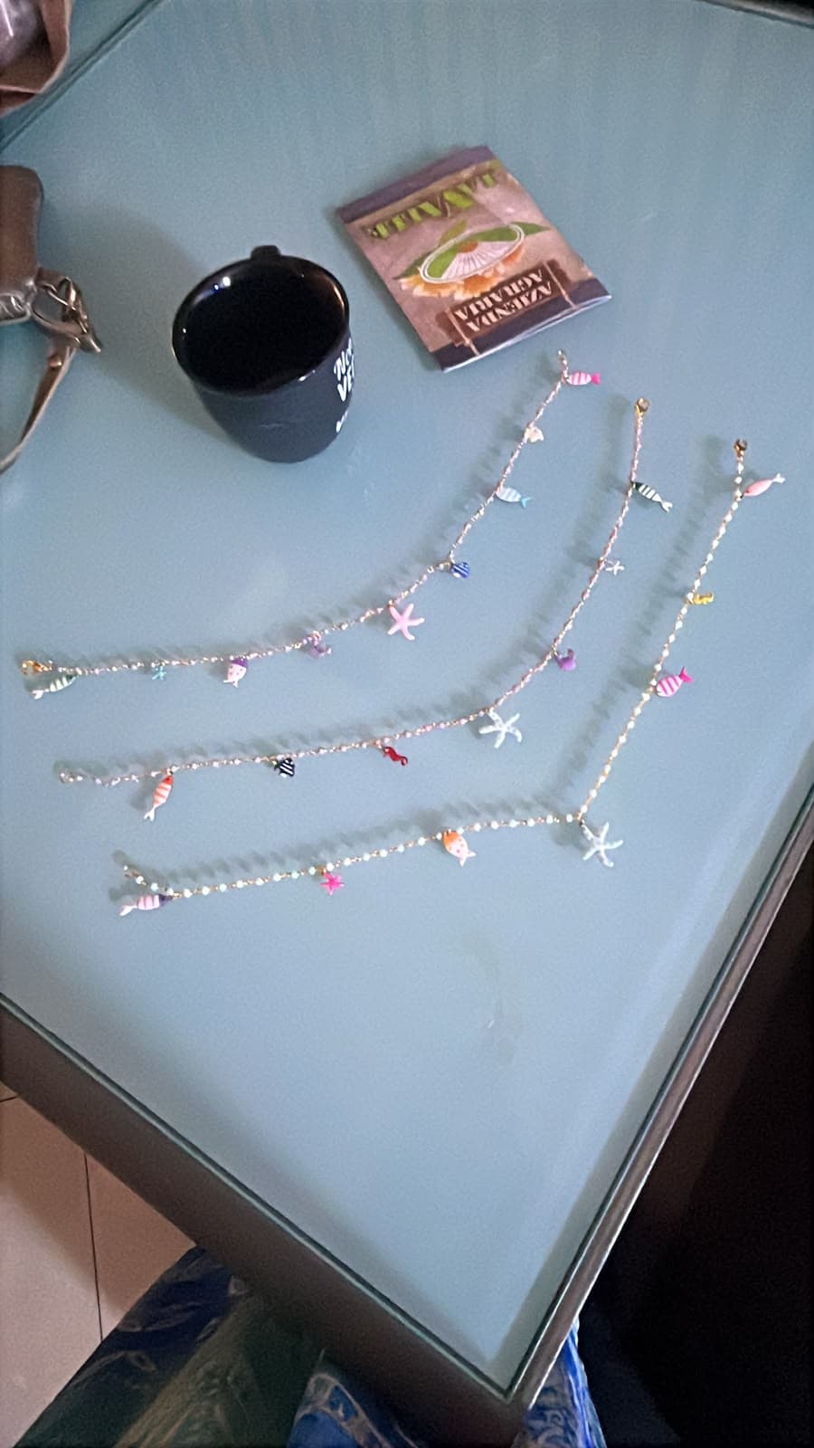 Piccoli elementi chiari e pendenti marini, con stella rosa. La scheda riguarda il solo filo in alto nella foto originale; gli altri gioielli non sono inclusi.